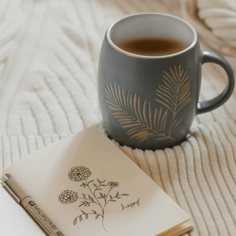 Cup filed with a drink resting on a natural coloured blanket